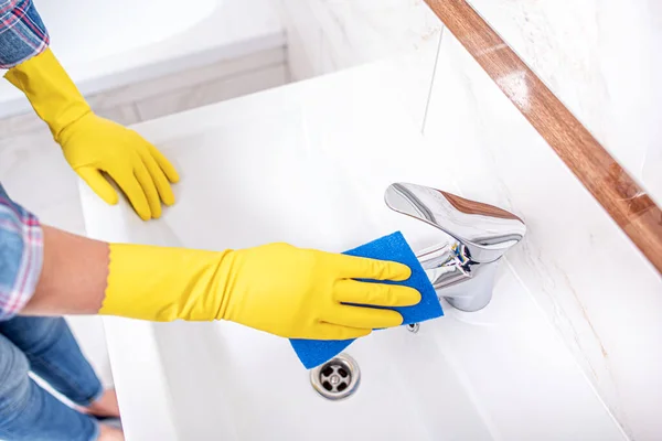 Cleaning in the bathroom. A woman wipes the sink and washbasin faucet. — Stock Photo, Image