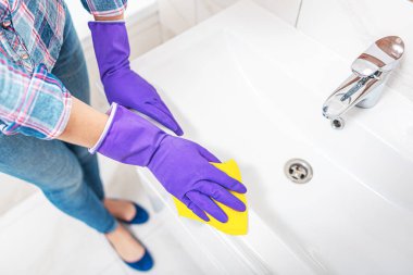 Banyoyu temizliyorum. Bir kadın lavaboyu ve lavaboyu siliyor..