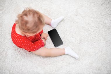 Küçük kız akıllı telefondan bir şey izliyor..