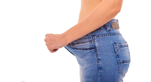 Fille mince en gros jeans sur un fond blanc. Perdre du poids . — Photo