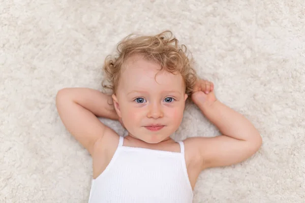 Portrait of a little girl who lies on the carpet — Stock Photo, Image