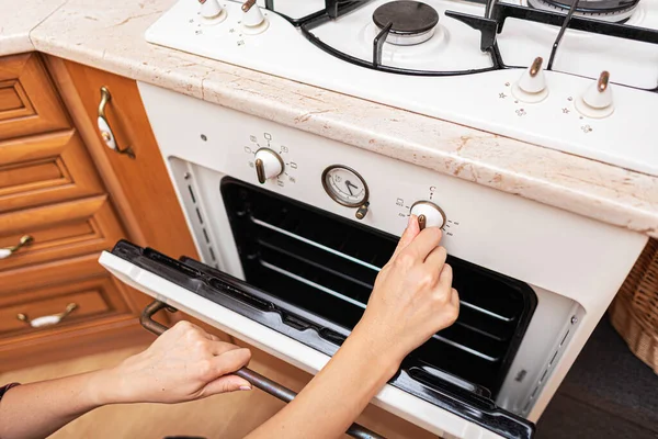 Kadın mutfaktaki fırını kullanıyor..