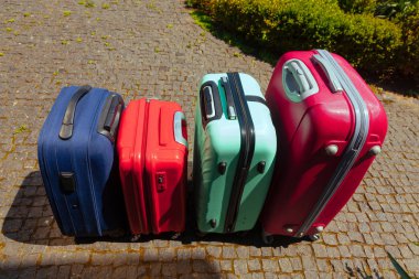 Dört renkli valizleri evin önünde dur. Bagaj yakınındaki aile otomobili tatil gezi için hazır.
