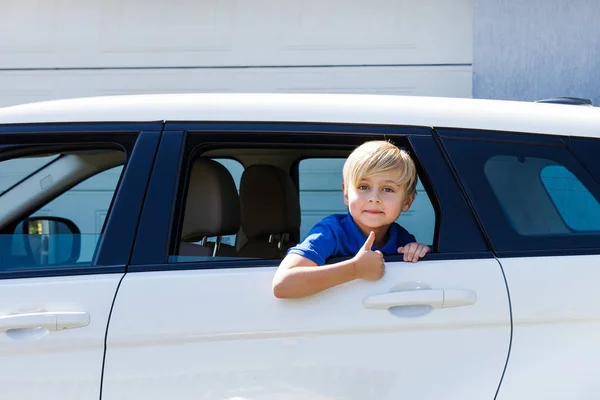 Boy blond in an open box of a car. Funny kids in the car with a hand gesture ok.