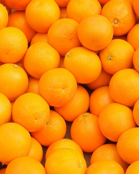 Parlak sarı-turuncu paleti birçok bütün portakal. Güneş ışığı altında açık havada bir piyasa ahır içinde bir yığında iştah açıcı olgun portakal.