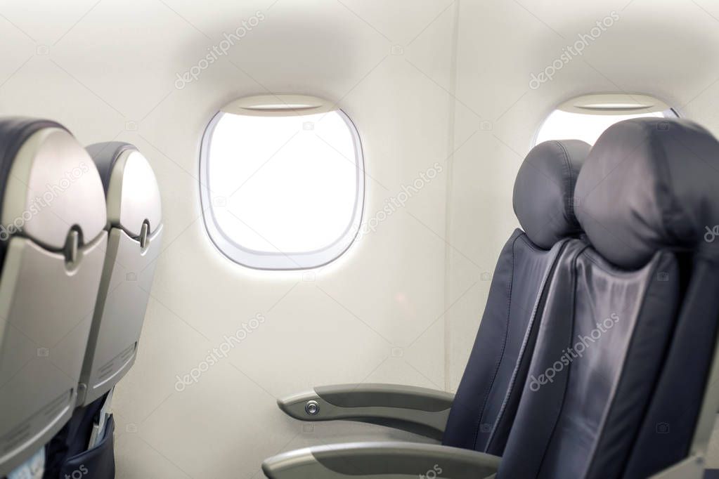 Porthole in the passenger cabin with empty seats. Passengers inside the cabin of a commercial airliner during flight.