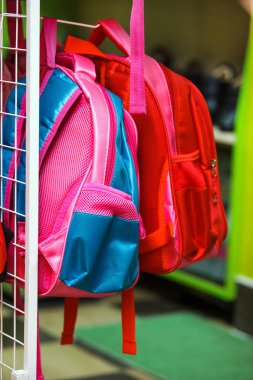 Many pink backpacks on the shelf in the supermarket. clipart