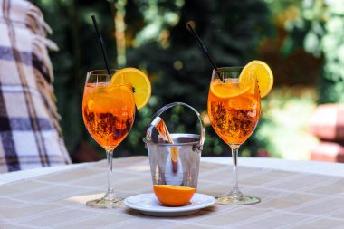 Aperol spritz kokteyl cam ahşap masa üzerinde. İki kadeh kokteyl ve masanın üzerine bir buz kovası.