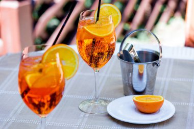 Aperol spritz kokteyl cam ahşap masa üzerinde. İki kadeh kokteyl ve masanın üzerine bir buz kovası.