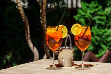 Aperol spritz kokteyl cam ahşap masa üzerinde. İki kadeh kokteyl ve masanın üzerine bir buz kovası.