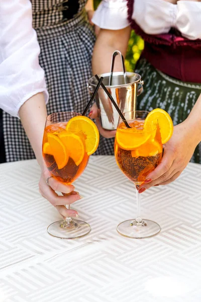 Aperol 在木桌上的玻璃杯里喷出鸡尾酒 服务员的手放在桌上的橙色鸡尾酒 — 图库照片