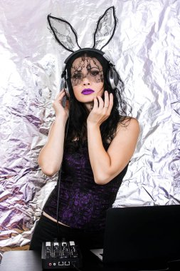 Esmer Dj dantel maskesi ve mor korse, Cadılar Bayramı kutluyor. Oyun ve müzik karıştırma kadın Dj. Cadılar Bayramı kavramı.