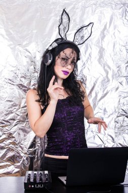 Esmer Dj dantel maskesi ve mor korse, Cadılar Bayramı kutluyor. Oyun ve müzik karıştırma kadın Dj. Cadılar Bayramı kavramı.