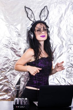 Esmer Dj dantel maskesi ve mor korse, Cadılar Bayramı kutluyor. Oyun ve müzik karıştırma kadın Dj. Cadılar Bayramı kavramı.