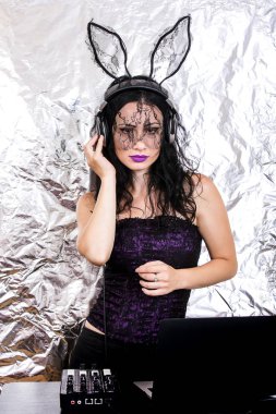 Esmer Dj dantel maskesi ve mor korse, Cadılar Bayramı kutluyor. Oyun ve müzik karıştırma kadın Dj. Cadılar Bayramı kavramı.