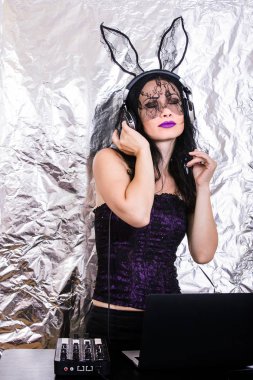 Esmer Dj dantel maskesi ve mor korse, Cadılar Bayramı kutluyor. Oyun ve müzik karıştırma kadın Dj. Cadılar Bayramı kavramı.