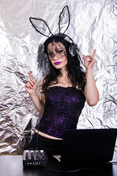 Esmer Dj dantel maskesi ve mor korse, Cadılar Bayramı kutluyor. Oyun ve müzik karıştırma kadın Dj. Cadılar Bayramı kavramı.