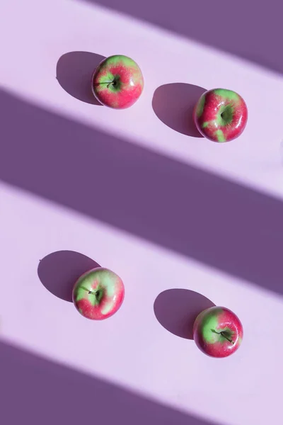 Ripe yellow and red apples on a lilac background, light and shadow concept.