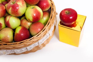 Beyaz zemin üzerinde bir sepet içinde kırmızı ve Sarı elmalar. Altın hediye kutusu ile sulu meyve Close-up.