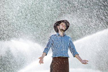 Şapkalı çiftçi yağmur keyif alıyor. Yaz aylarında yağmur altında ıslak genç adam.