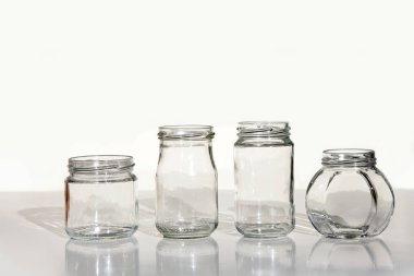 Dört cam kavanoz gölge beyaz masada temizlemek. Beyaz arka plan üzerinde izole boş kavanoz set.