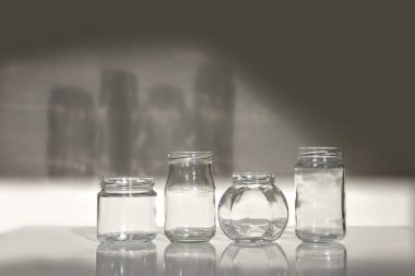 Dört cam kavanoz gölge beyaz masada temizlemek. Beyaz arka plan üzerinde izole boş kavanoz set.