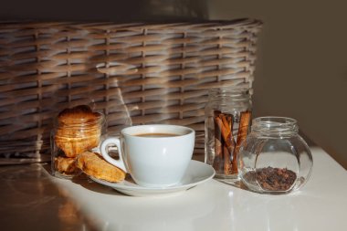 Sütlü çay bir fincan şeker ve baharat şeffaf kavanozlara sopalarla. Fincan kahve ve beyaz arka plan üzerinde cam kavanoz içine tarçın.