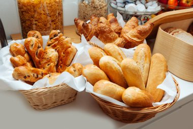 Baker pişirme taze kruvasanlar ve Çörekler fırından çıkardım. Kadınların elleri beyaz eldiven bir sepet sıcak hamur işleri ile tutun