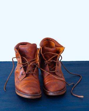 Old red dirty high shoes on blue background. Old school vintage worn boots with leather laces.