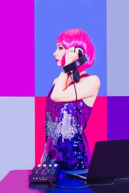 Göz alıcı Dj kız pembe saçlı ve headphne kırmızı, pembe ve mavi arka plan müzik disko çalış..