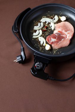 Elektrikli tava etli tablo. Herhangi bir yerde yemek pişirmek için bağımsız yardımcı tava.