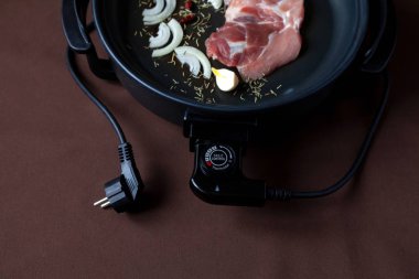 Elektrikli tava etli tablo. Herhangi bir yerde yemek pişirmek için bağımsız yardımcı tava.