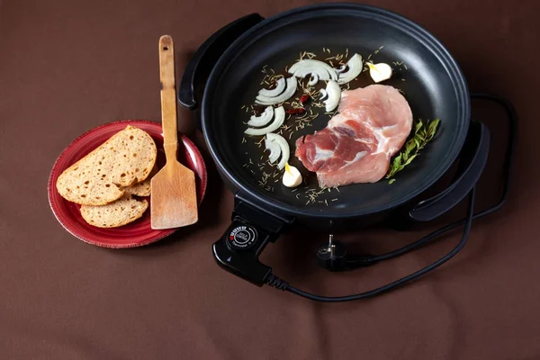 Elektrikli tava etli tablo. Herhangi bir yerde yemek pişirmek için bağımsız yardımcı tava.