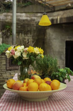 Portakal, elma ve biberiye ile bir tabloda bir vazoda sarı ve pembe teşkil etmektedir. Sandalye ve sahilde denize yakın tablo Cafe.