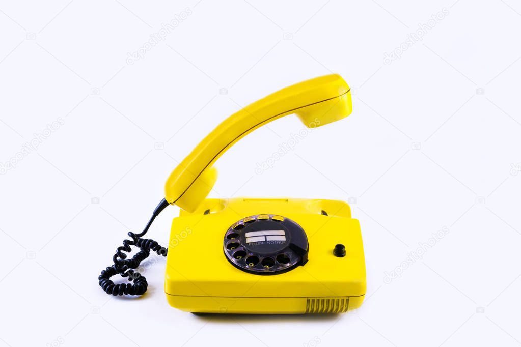 Retro vintage phone handset yellow plastic white disko background old style 90 telephone answer call raised