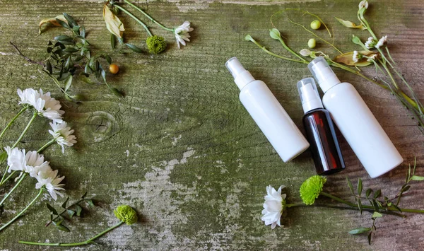 Contenitore cosmetico vaso spray dispenser fiori verdi bianco vecchio fondo di legno campagna lato — Foto Stock
