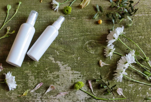 Recipiente cosmético frasco spray dispensador flores verdes branco velho fundo de madeira país lado — Fotografia de Stock