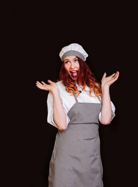 Молодая шеф-повар женщина черная униформа изолированный белый фон фартук шляпа эмоция улыбка — стоковое фото