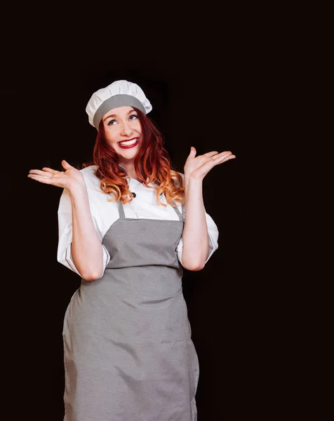 Молодая шеф-повар женщина черная униформа изолированный белый фон фартук шляпа эмоция улыбка — стоковое фото