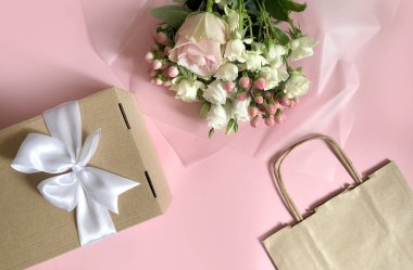 Pembe çiçekler, el işi kağıt torbaları ve pembe arka planda kutular. Müşteri Paketleme Hizmeti Konsepti.
