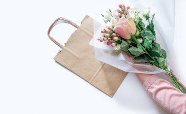 Teslimat İşçisi 'nin Beyaz Arkaplan' daki müşteri için kağıt torbaya çiçek paketleyen eli..