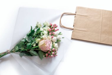 Beyaz arka planda bir buket Pembe Çiçek ve Kağıt Torba. Müşteri Paketleme Hizmeti Konsepti.