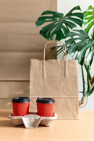 Craft Paper Bags stay near Two Red Cups of Coffee in container. Concept of Delivery Service Packing Order Take Away for Customer.