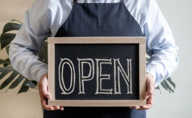 Kadın Elleri Metni Açık Gösterge Paneli Tutuyor. Önlüklü İşçi Kafe ya da Market Açılışını Gösteriyor.