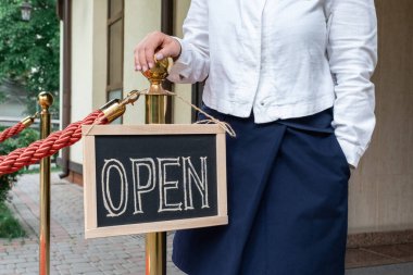 Kadının elleri metin açık bir şekilde gösterge panelini tutuyor. İşçi kafe ya da restoranın reklamını gösteriyor.