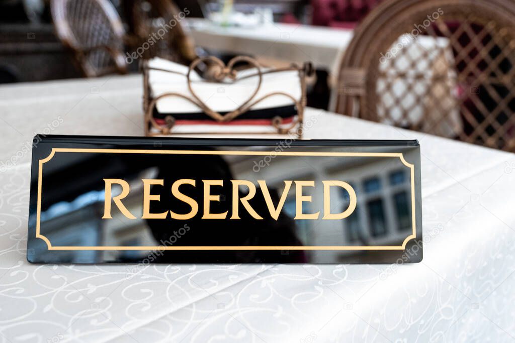 A tag of reservation placed on table. Reserved logo in a restaurant or summer terrace of cafe.