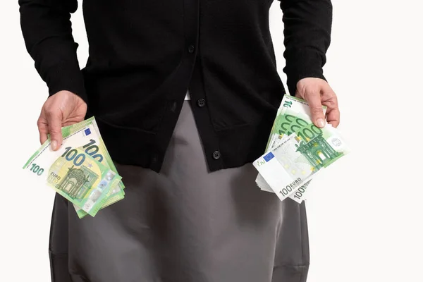 Woman's hand gets money from pockets in her clothes. The female hands holds euro.