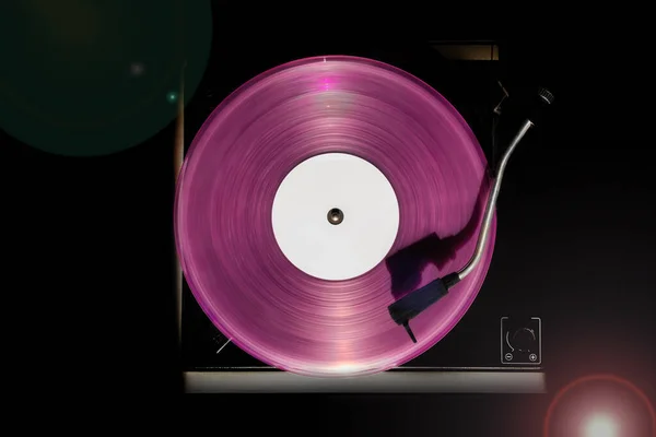 Vintage record player with pink vinyl record on the black background. Old school style.