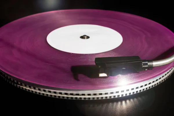 Vintage record player with pink vinyl record on the black background. Old school style.