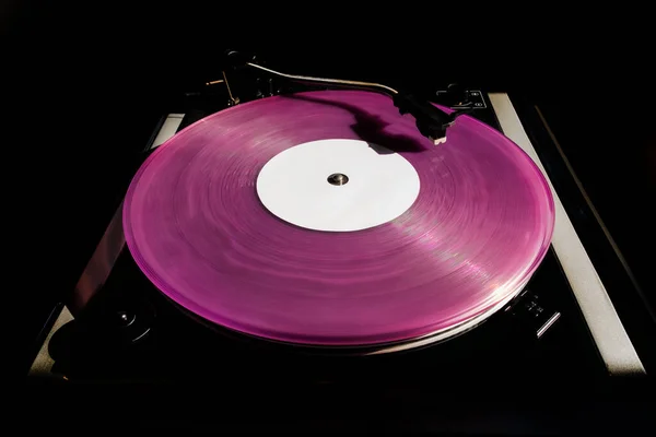 Vintage record player with pink vinyl record on the black background. Old school style.